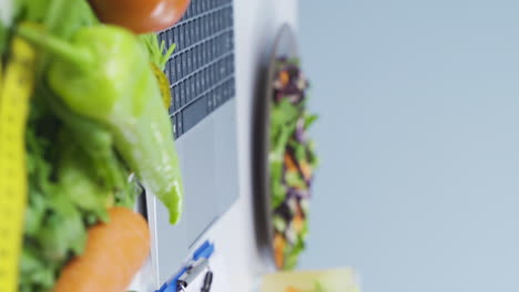 Vertical-video-of-Dietitian-preparing-diet-plan-on-laptop.